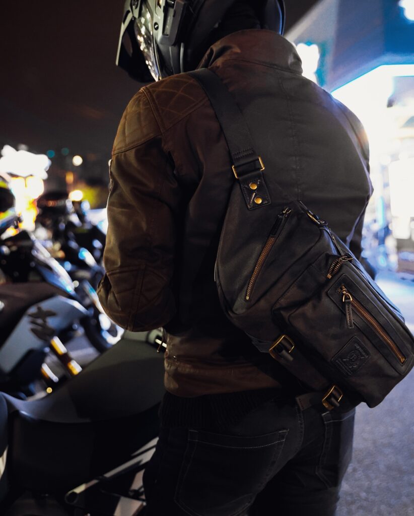 Builford Motorcycle Sling Bag Riding Motorcyclist riding cafe racer wearing Builford waxed canvas sling bag over leather jacket