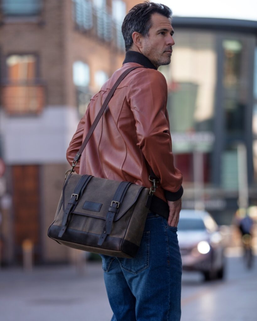 A man in a leather jacket carrying a Builford Bohemian bag in an urban setting