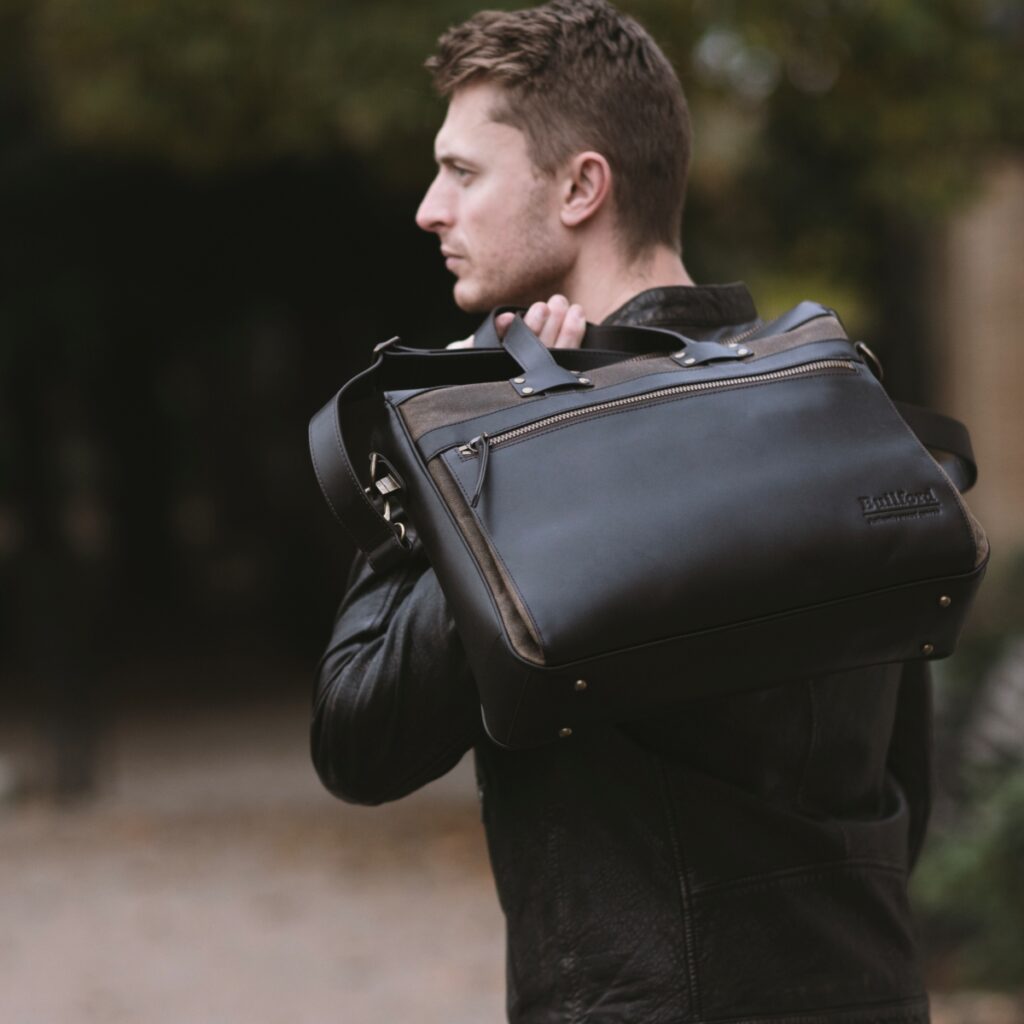 A man in a leather jacket carrying a Builford 628 Portfolio briefcase, showing a rugged yet professional commuter style