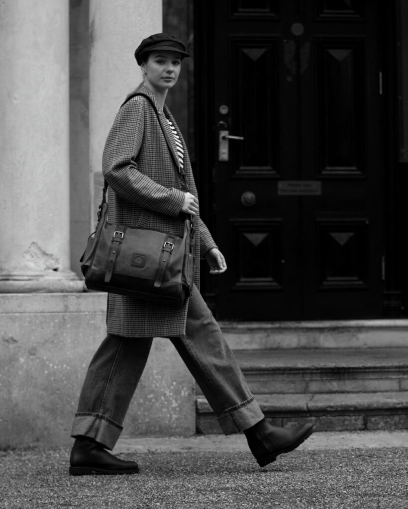 Black and white profile shot of a woman carrying a Builford waxed canvas and leather messenger bag.